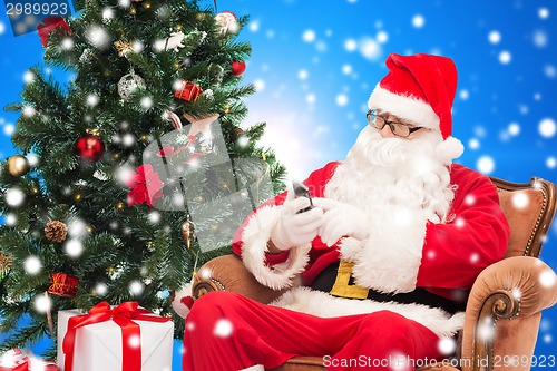 Image of santa claus with smartphone and christmas tree