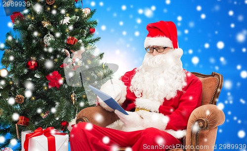 Image of man in costume of santa claus with tablet pc