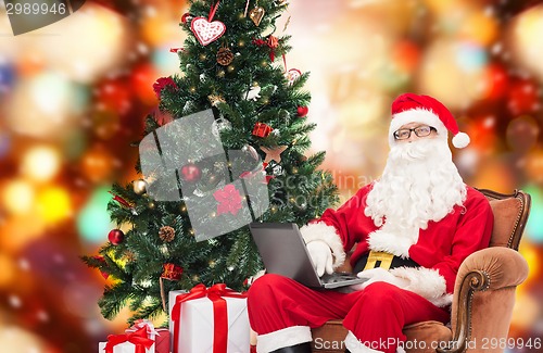 Image of man in costume of santa claus with laptop