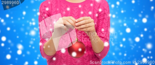 Image of close up of woman in sweater with christmas ball