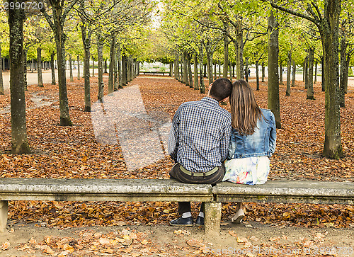 Image of Young Couple Sitting on a Bench in a Park in Autumn
