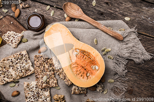 Image of Cut Pumpkin, honey, and cookies with seeds on wood