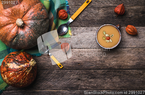 Image of Rustic style pumpkins and soup with seeds and ground cherry on w