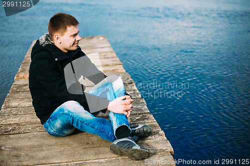 Image of Young Handsome Man Sitting On Wooden Pier, Relaxing,  Thinking, 