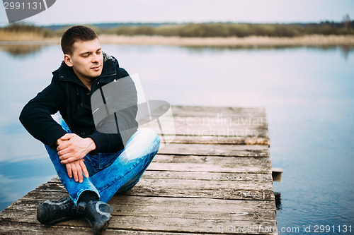 Image of Young Handsome Man Sitting On Wooden Pier, Relaxing,  Thinking, 