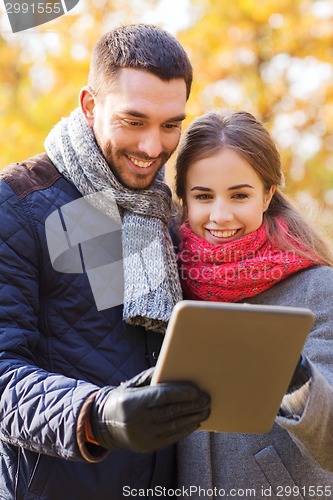 Image of smiling couple with tablet pc in autumn park