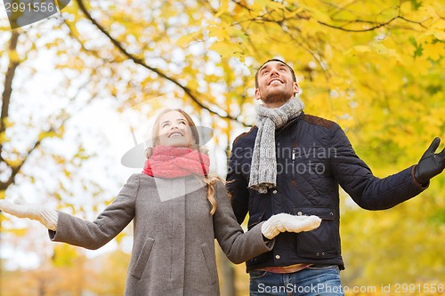 Image of smiling couple looking up in autumn park