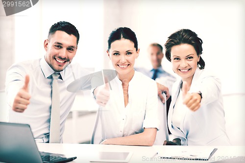Image of business team showing thumbs up in office
