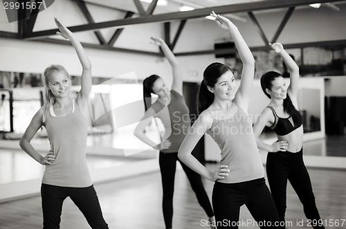 Image of group of smiling people stretching in the gym
