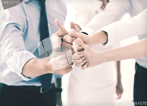 Image of business team showing thumbs up in office