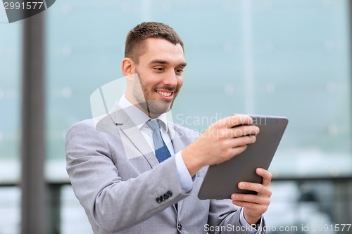 Image of smiling businessman with tablet pc outdoors