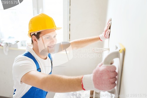 Image of smiling builder with grinding tool indoors