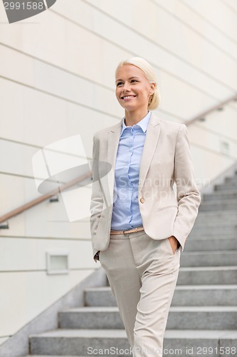 Image of young smiling businesswoman walking down stairs