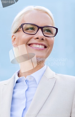 Image of young smiling businesswoman over office building