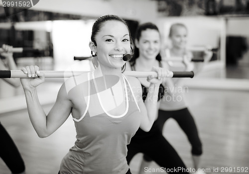 Image of group of smiling people working out with barbells