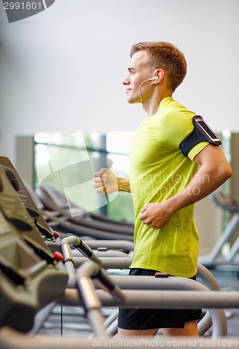 Image of smiling man exercising on treadmill in gym
