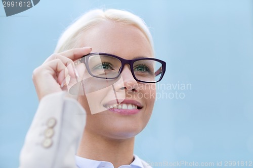 Image of young smiling businesswoman over office building