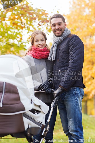 Image of smiling couple with baby pram in autumn park