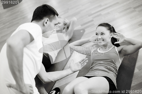 Image of group of smiling women doing sit ups in the gym