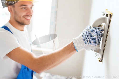 Image of smiling builder with grinding tool indoors