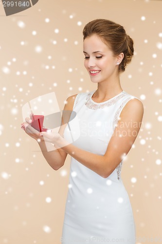 Image of smiling woman holding red gift box with ring