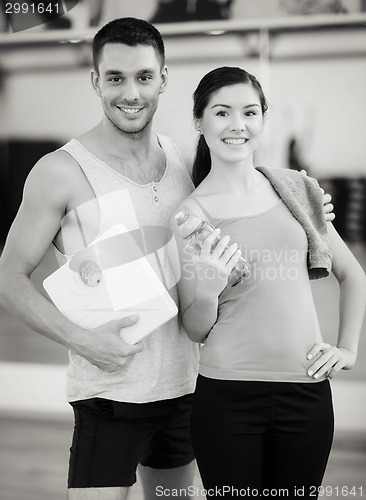 Image of two smiling people with scale in the gym