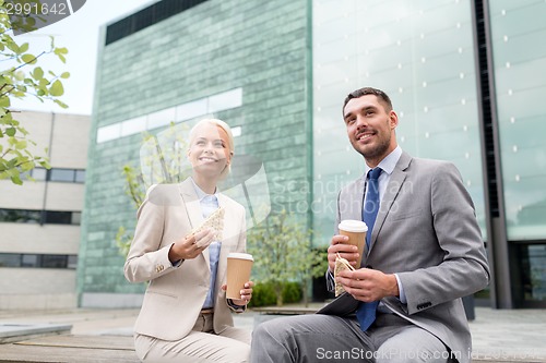 Image of smiling businessmen with paper cups outdoors