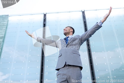 Image of young smiling businessman over office building