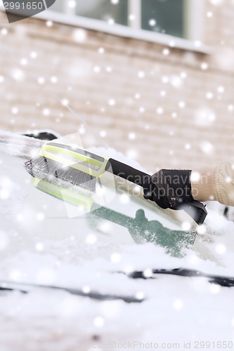 Image of closeup of man cleaning snow from car