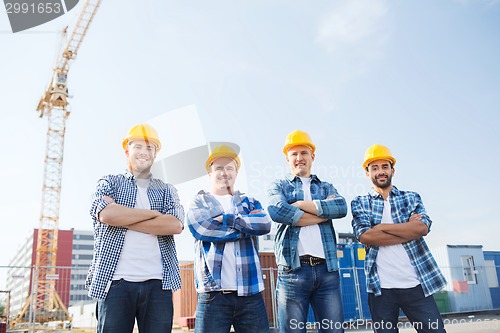 Image of group of smiling builders in hardhats outdoors