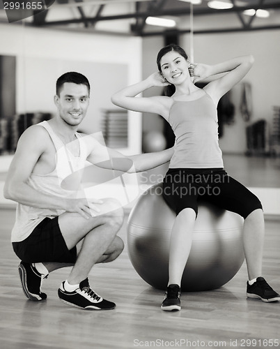 Image of male trainer with woman doing crunches on the ball