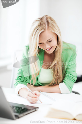Image of smiling student girl writing in notebook
