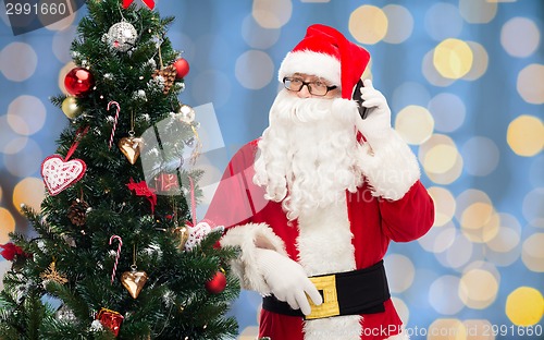 Image of santa claus with smartphone and christmas tree