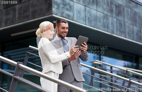 Image of smiling businessmen with tablet pc outdoors