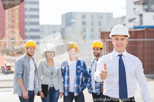 Image of group of smiling builders in hardhats outdoors