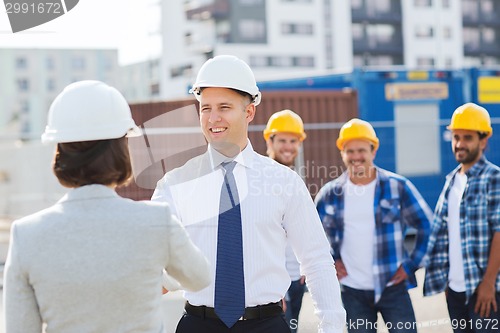 Image of group of smiling builders in hardhats outdoors