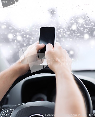 Image of close up of man using smartphone while driving car