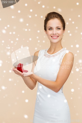 Image of smiling woman holding red gift box with ring