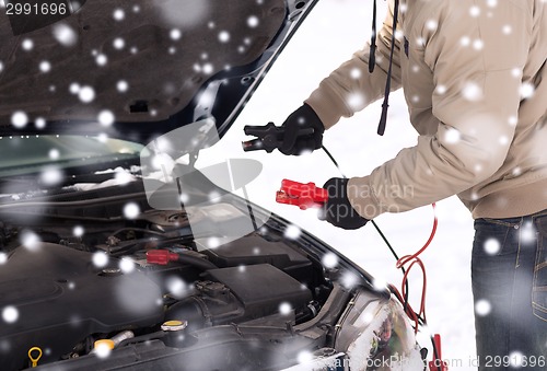 Image of closeup of man under bonnet with starter cables