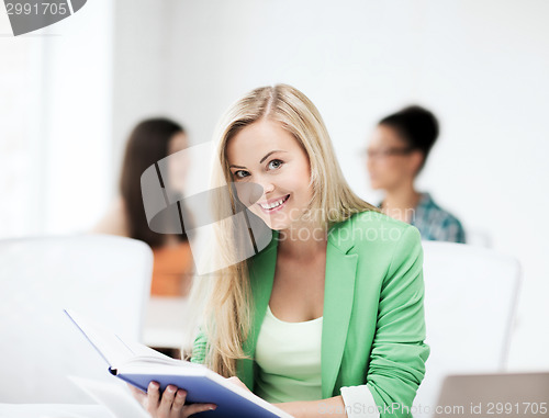 Image of smiling student girl reading book at school