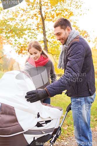 Image of smiling couple with baby pram in autumn park