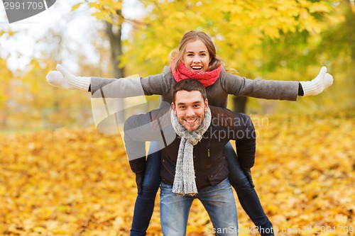 Image of smiling couple having fun in autumn park