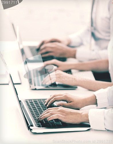 Image of group of people working with laptops in office