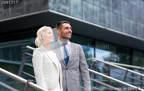 Image of smiling businessmen standing over office building