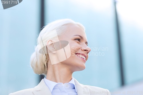 Image of young smiling businesswoman over office building