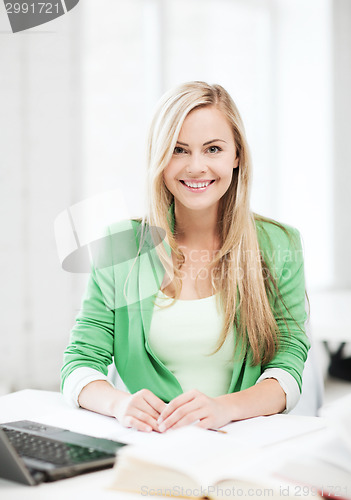 Image of smiling student girl with laptop at school