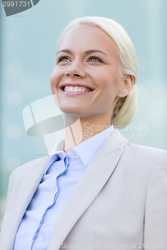 Image of young smiling businesswoman over office building