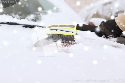 Image of closeup of man cleaning snow from car