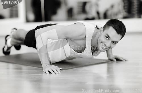 Image of smiling man doing push-ups in the gym