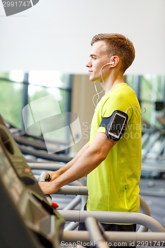 Image of man with smartphone exercising on treadmill in gym